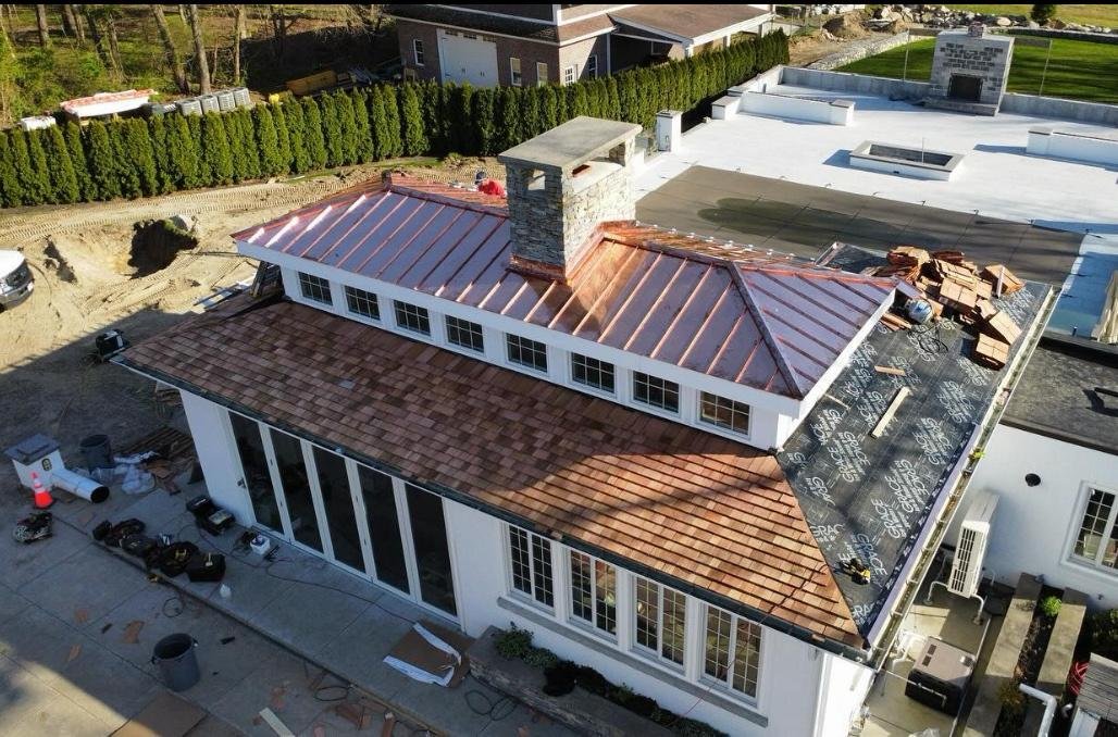 Copper standing seam and cedar shingle roof installation, aerial view